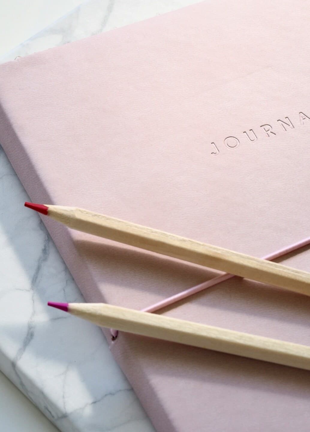 A journal, featuring a blank notebook, and pens, on a desk.